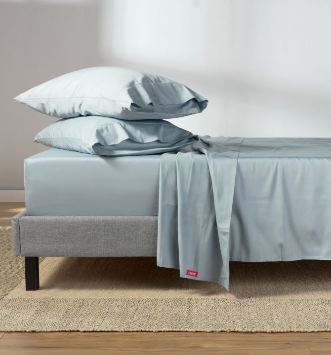 Blue percale sheets, 2 pillows with blue pillowcases on top of a grey bed frame