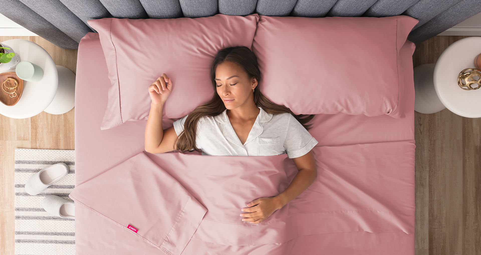 A woman sleeping in bed, dressed with the Endy Sheet Set in Cherry Blossom.