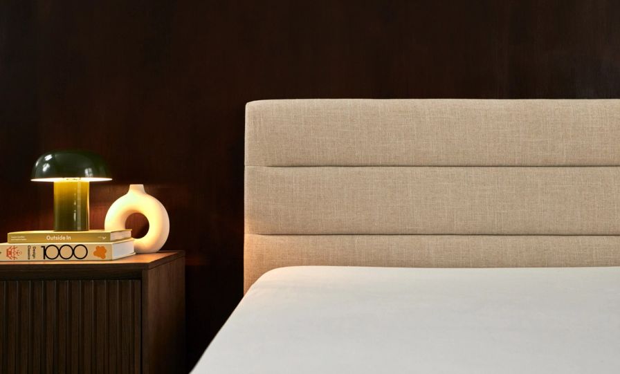 Bedroom with channel upholstered bed frame in alabaster colourway, shown with wooden nightstand.