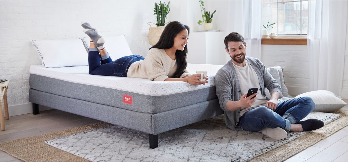 Two people relaxing on an Endy Platform bed outfitted with an Endy Mattress.