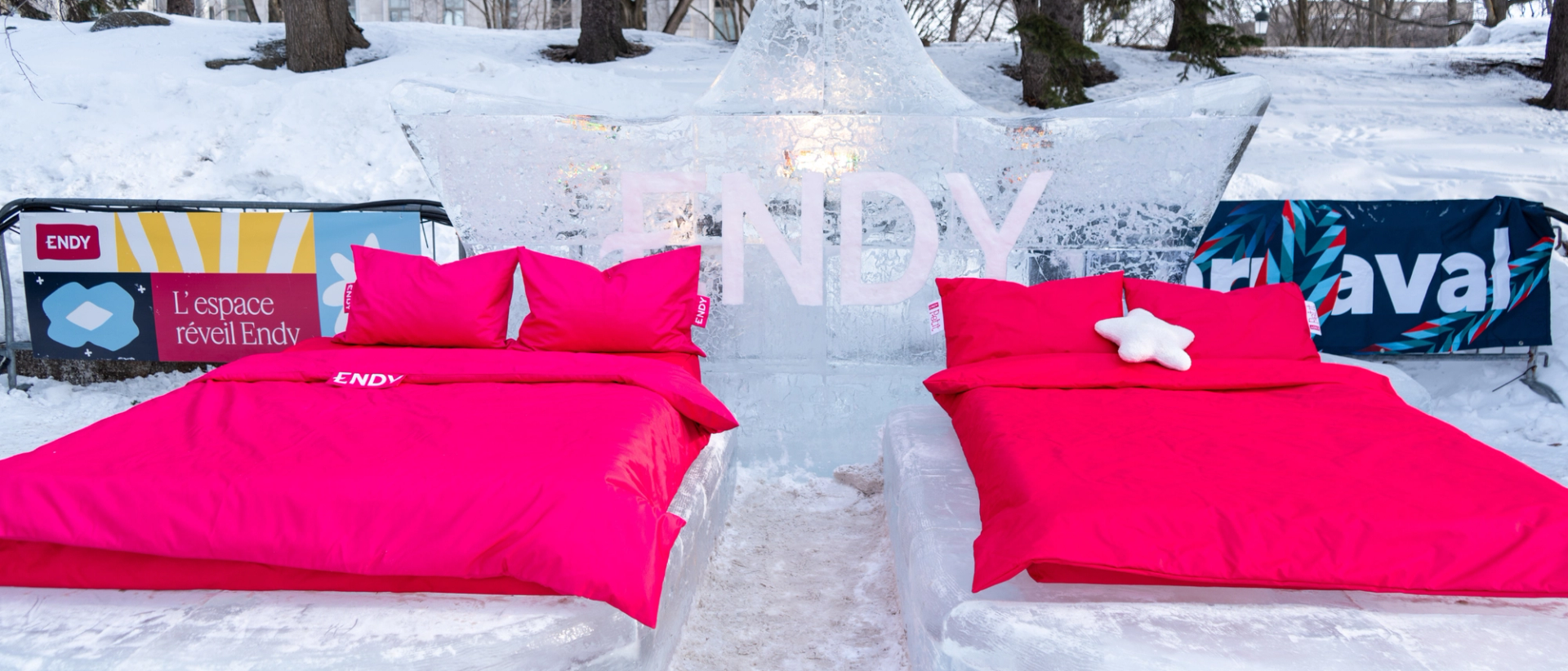 Two beds with magenta duvets are set up on bed frames made of ice with an ice sculpture behind it that says Endy
