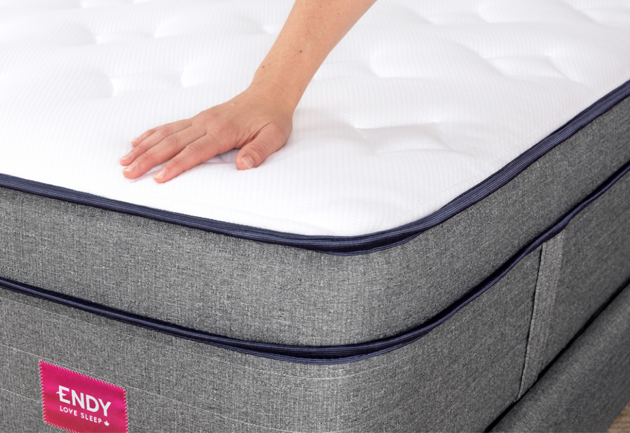 Hand showing the mattress sink of the Medium-Firm Endy Hybrid Mattress variant.