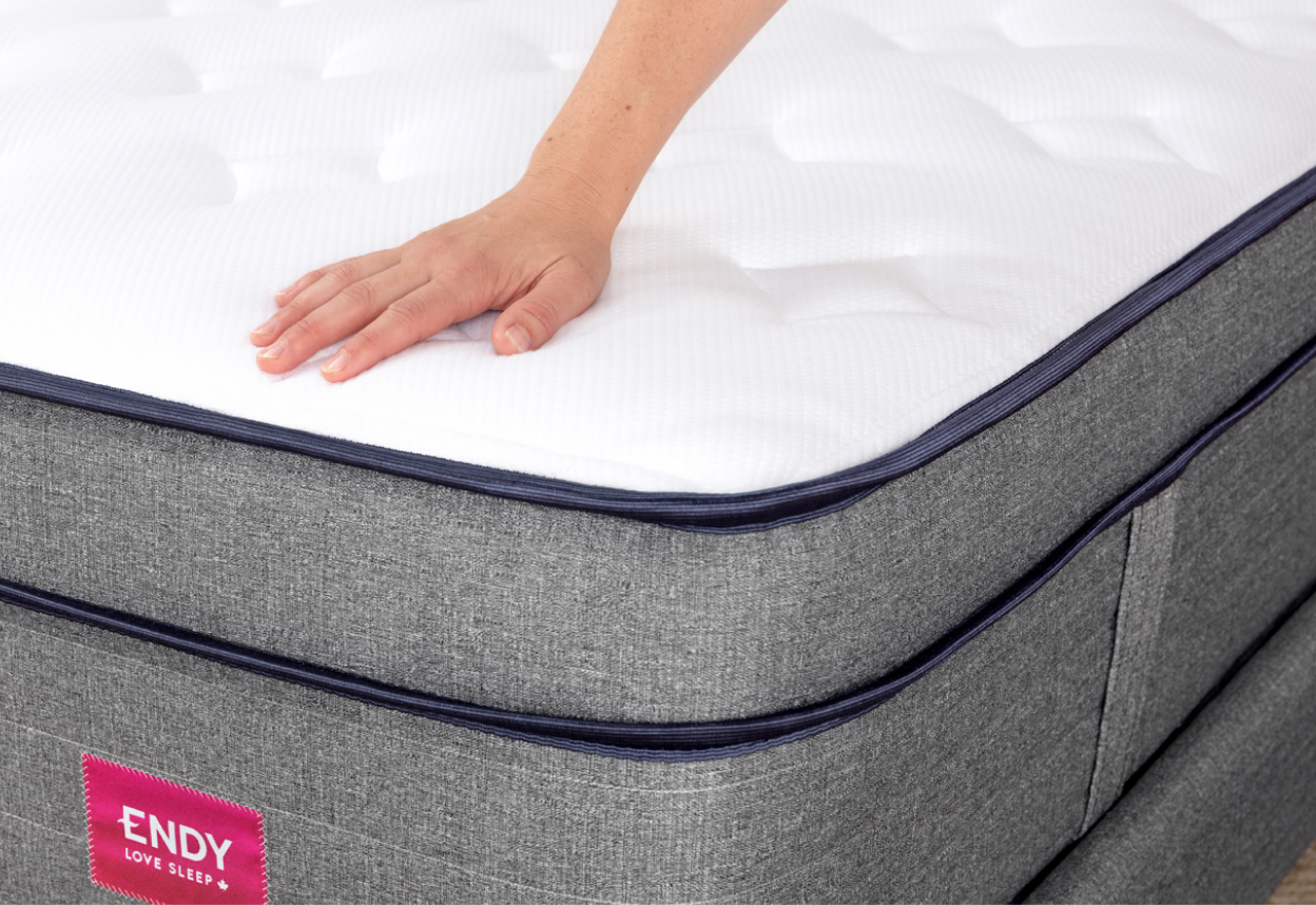 Main montrant l’enfoncement du matelas hybride Endy version mi-ferme.