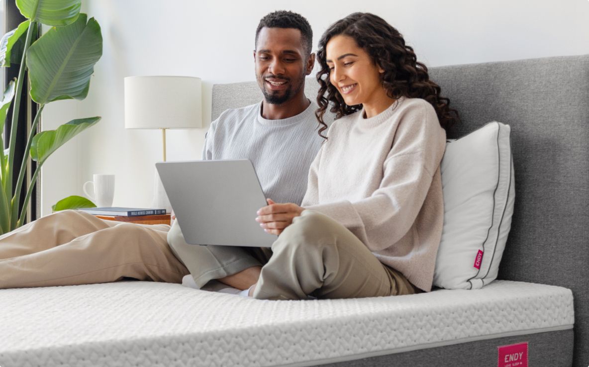 Two people browsing endy.com on an Endy Mattress with Endy's collection of sleep products.