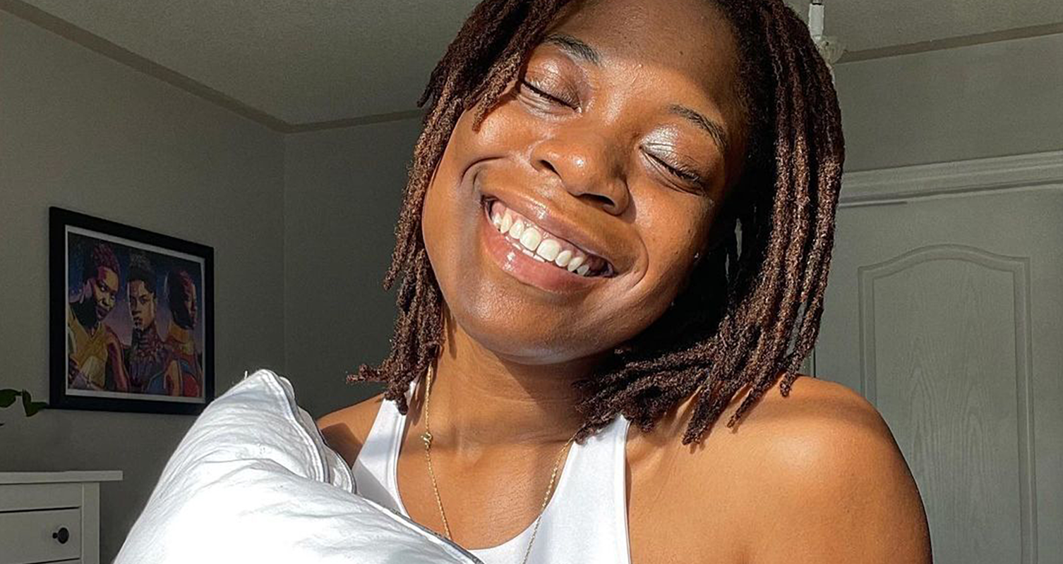 A woman's face, lit by sunlight, closing her eyes and smiling