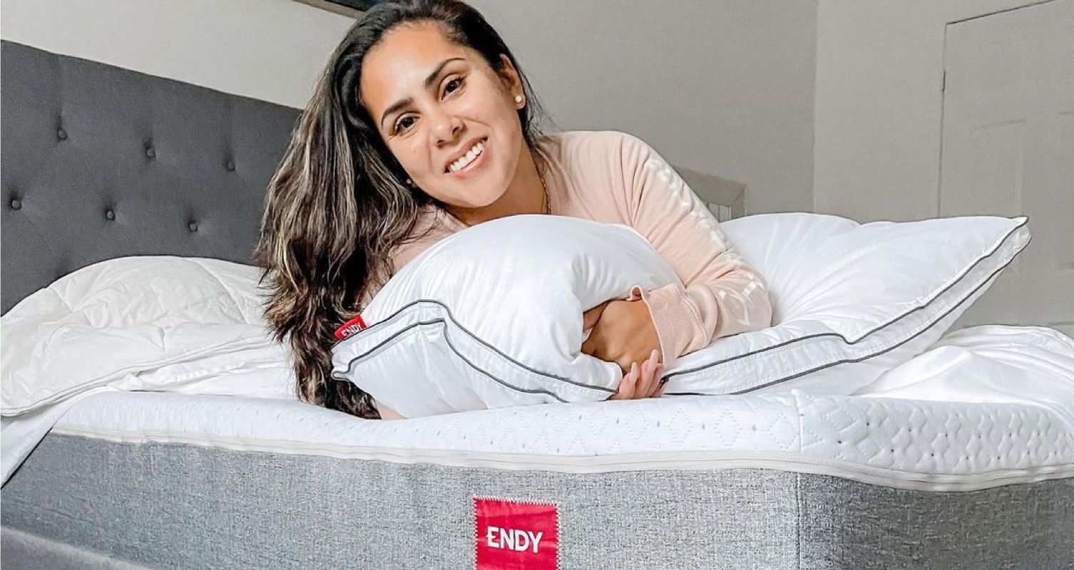 Image of a woman lying on an Endy mattress, hugging a pillow.