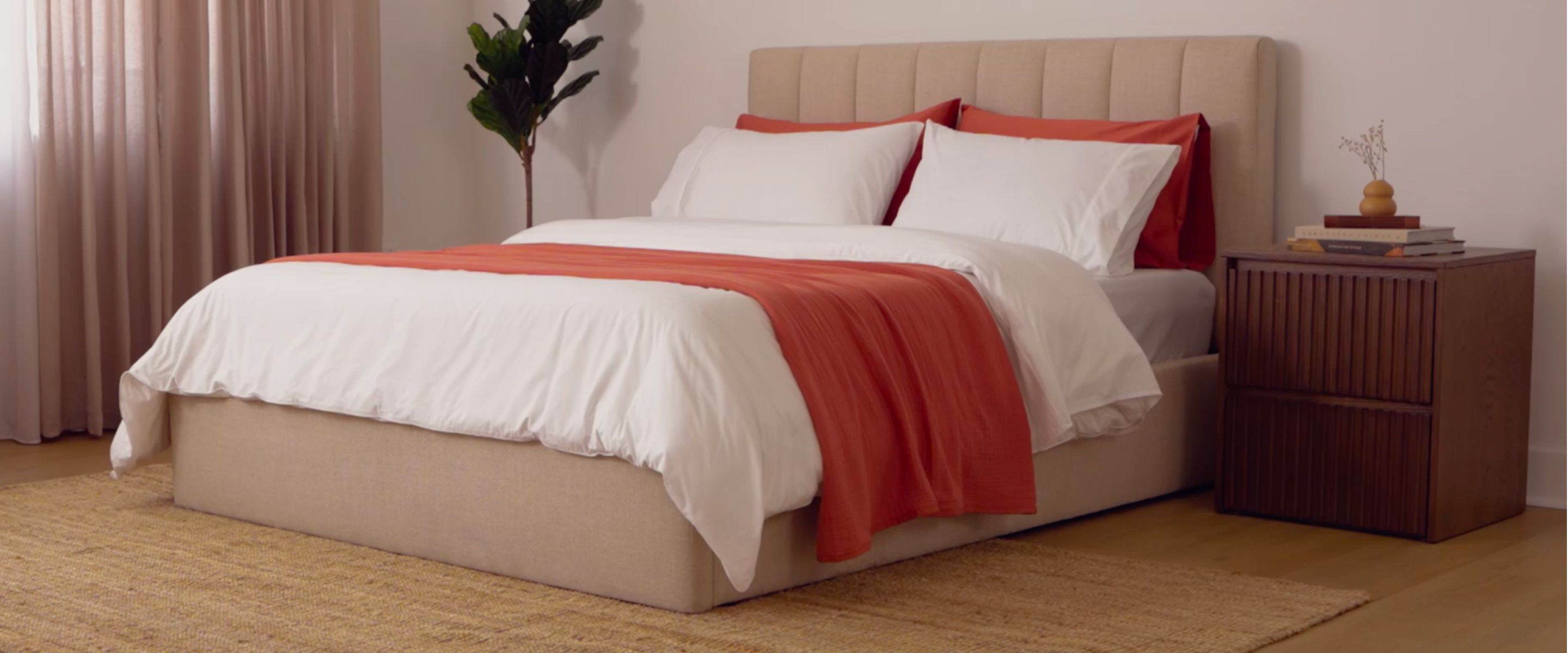 Fully dressed bed with white duvet cover and a Warm Ember Muslin blanket draped across it