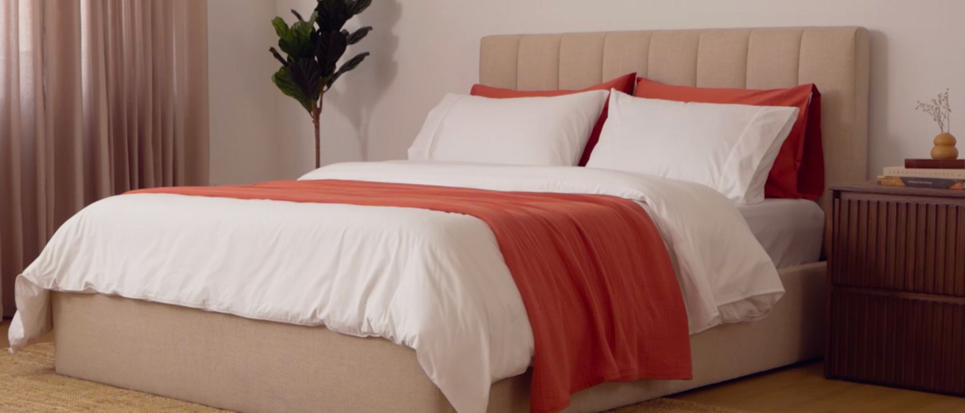 Fully dressed bed with white duvet cover and a Warm Ember Muslin blanket draped across it