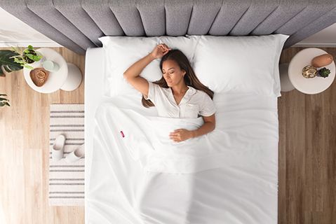 A woman sleeping in bed, viewed from above, wrapping in Endy Organic Cotton Sheets.