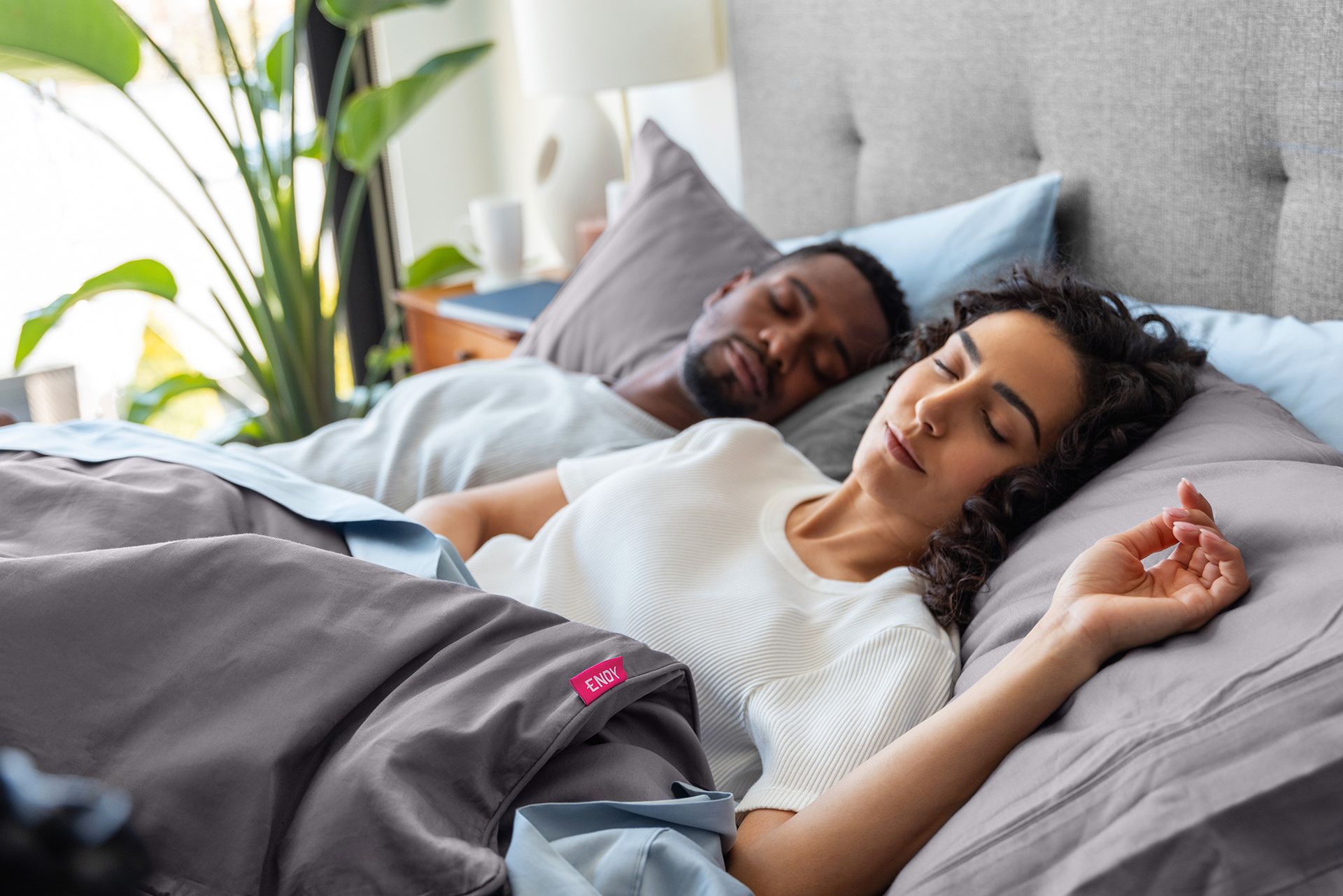 Two people snoozing in a bed that's outfitted with Endy's collection of sleep products.