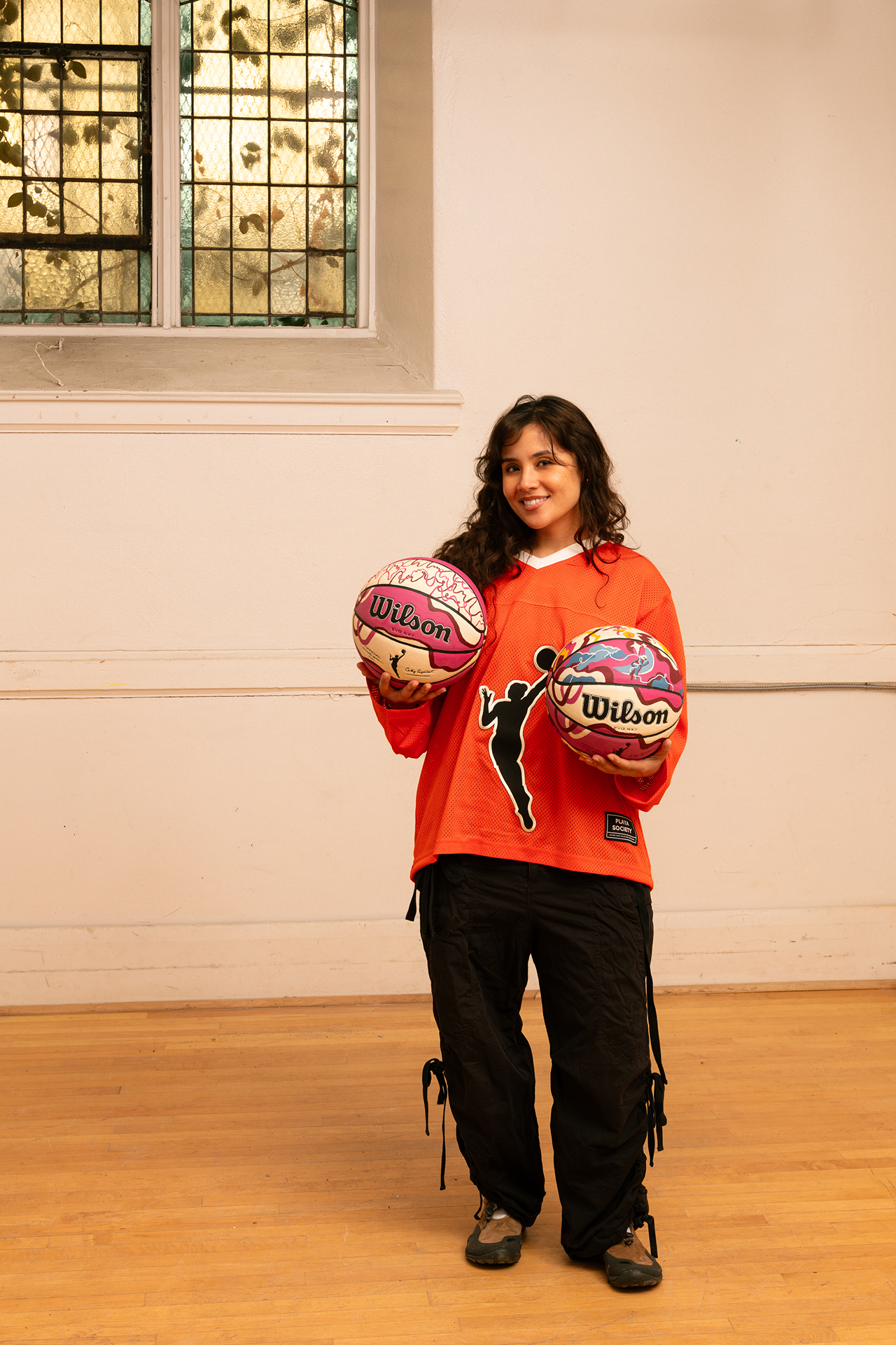 Artist Erika Flores holds two custom Endy x WNBA basketballs that she designed.