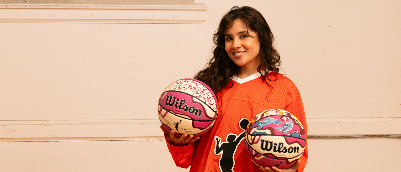 Artist Erika Flores holds two custom Endy x WNBA basketballs that she designed.