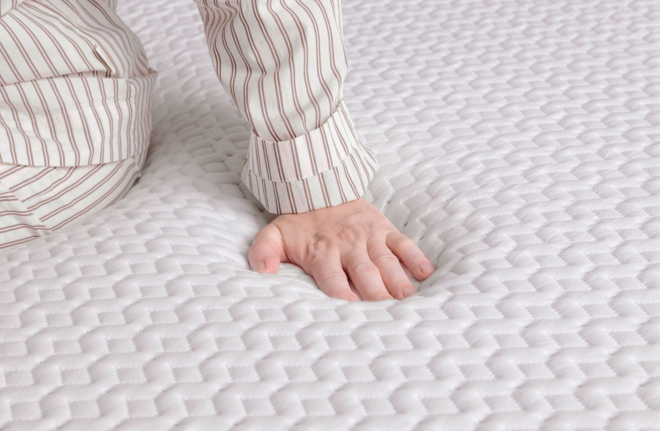 Hand pressing into the Endy Mattress to show foam responsiveness.