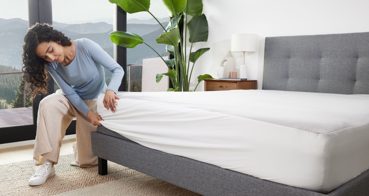 A woman putting an Endy Mattress Protector on her Endy Mattress.