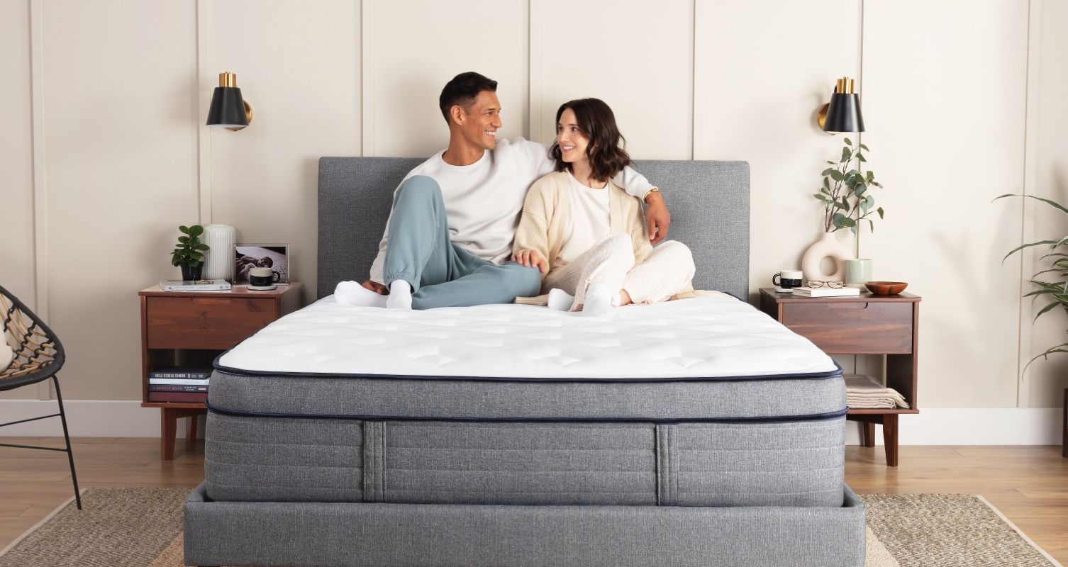 Man and woman sitting on the Endy Hybrid Mattress
