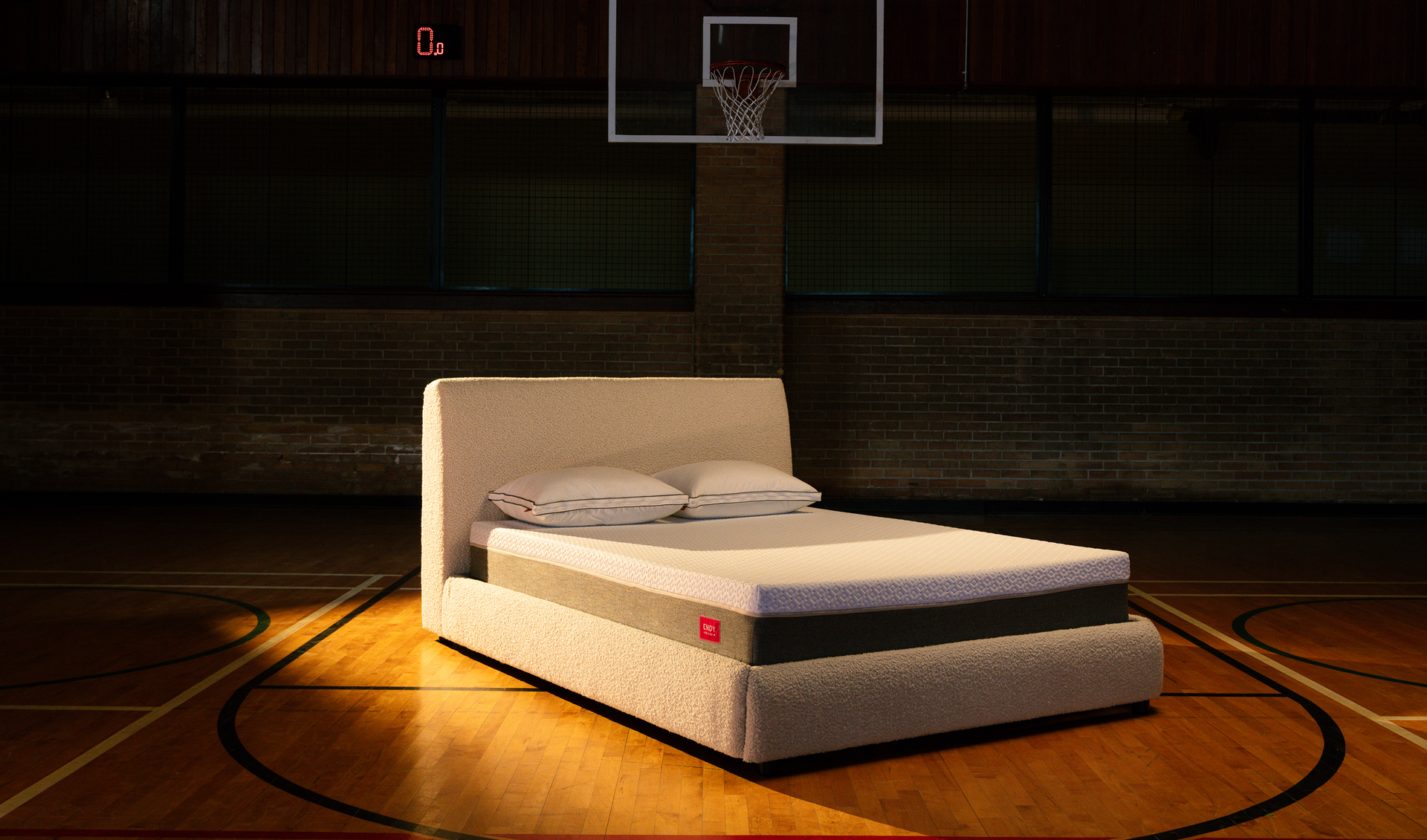 Bare Endy mattress on a white upholstered bed frame on a basketball court