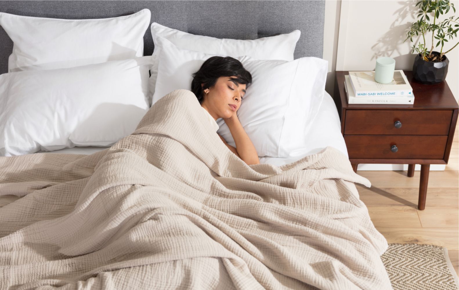 Person sleeping restfully on an endy foam mattress and pillows under a muslin blanket