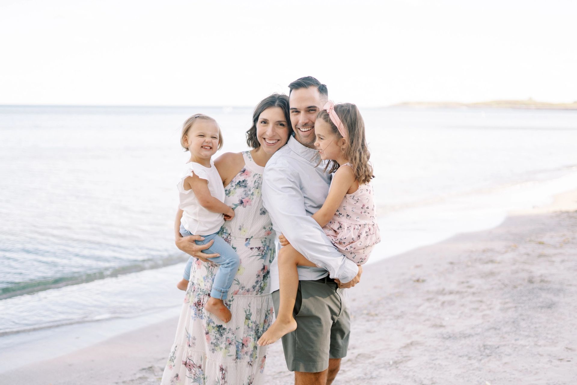 Jason with his wife and two daughters wearing semi-formal attire at the beach