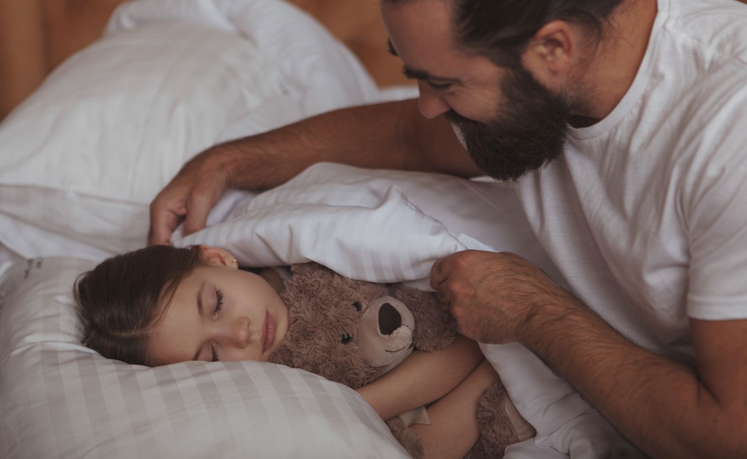 A parent putting a child to bed.