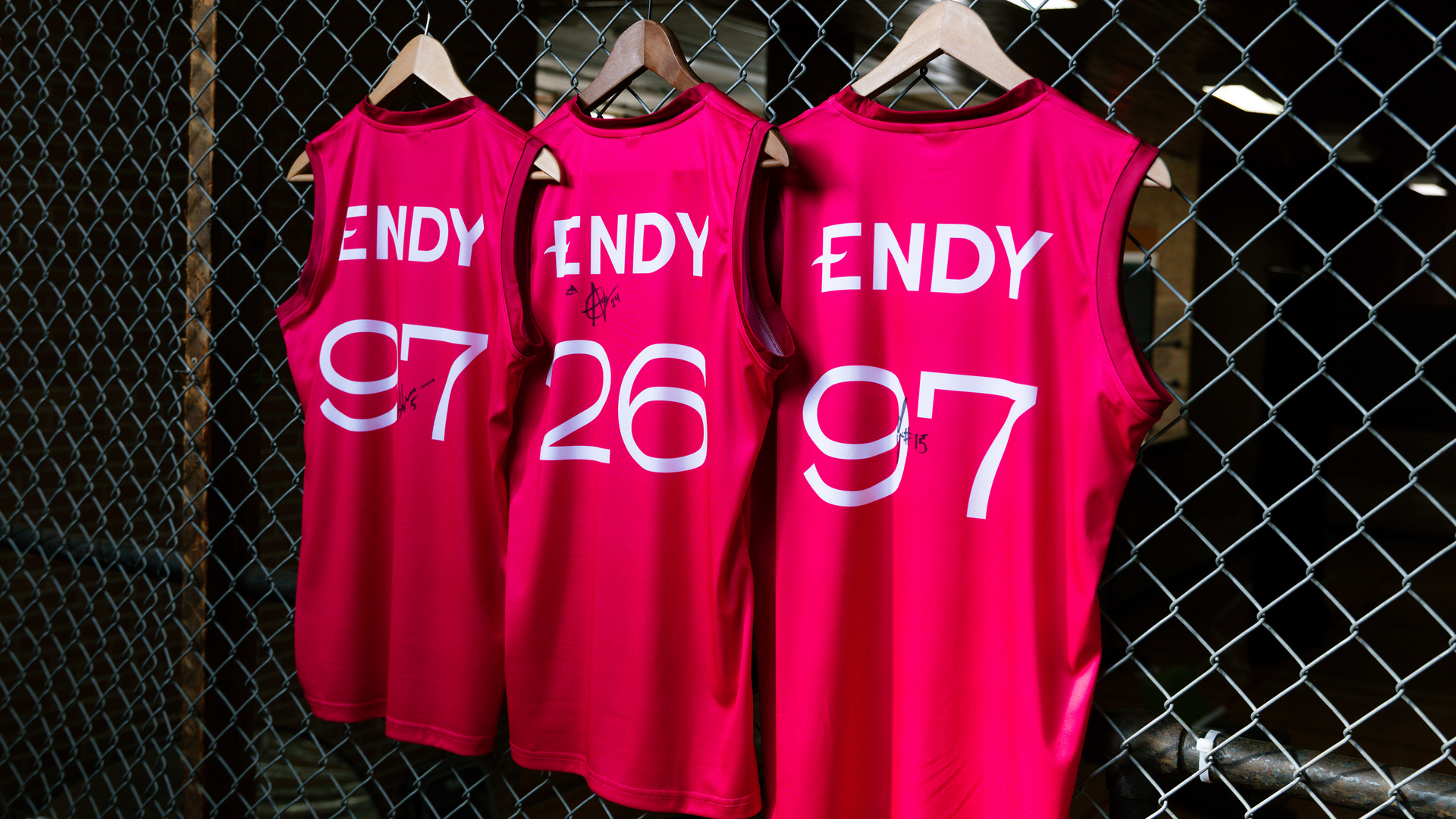 3 signed Endy basketball jerseys hanging on a chainlink fence