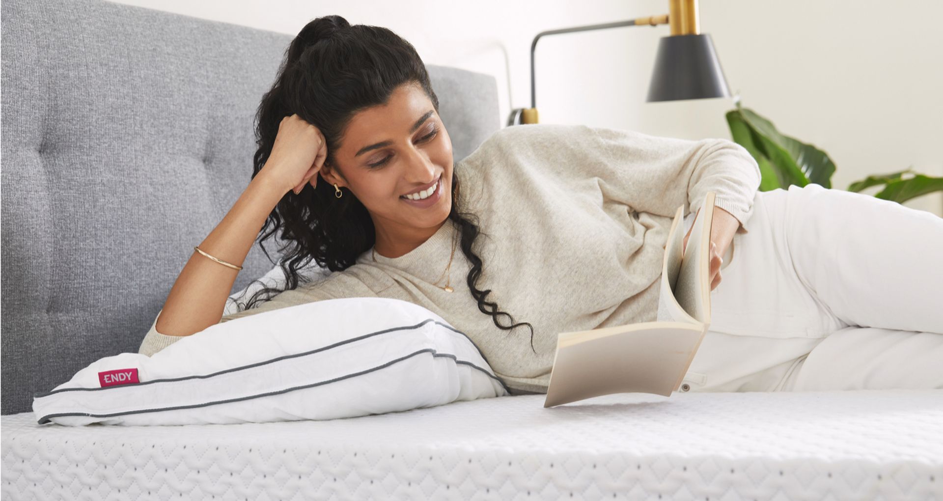 A person reading in bed with an Endy Customizable Pillow.