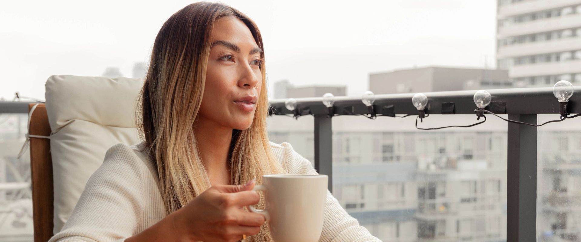 Christina Cheng holds a mug of coffee aloft while sitting on her apartment balcony.