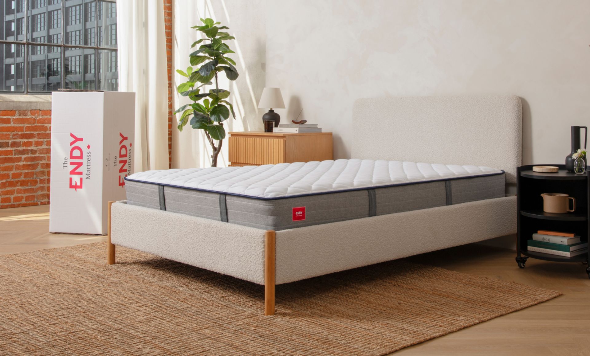 Bare Endy Hybrid mattress on a white bed frame in a minimalistic bedroom, with an Endy box behind the bed