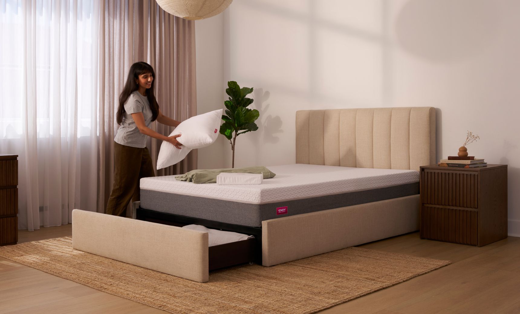 Woman placing a pillow onto the Endy Upholstered Storage Bed