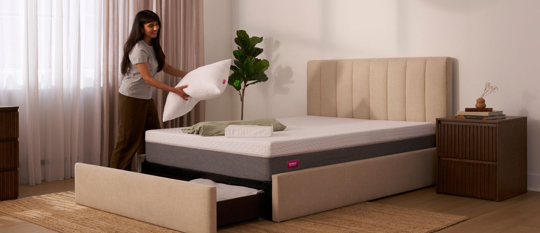 Woman placing a pillow onto the Endy Upholstered Storage Bed