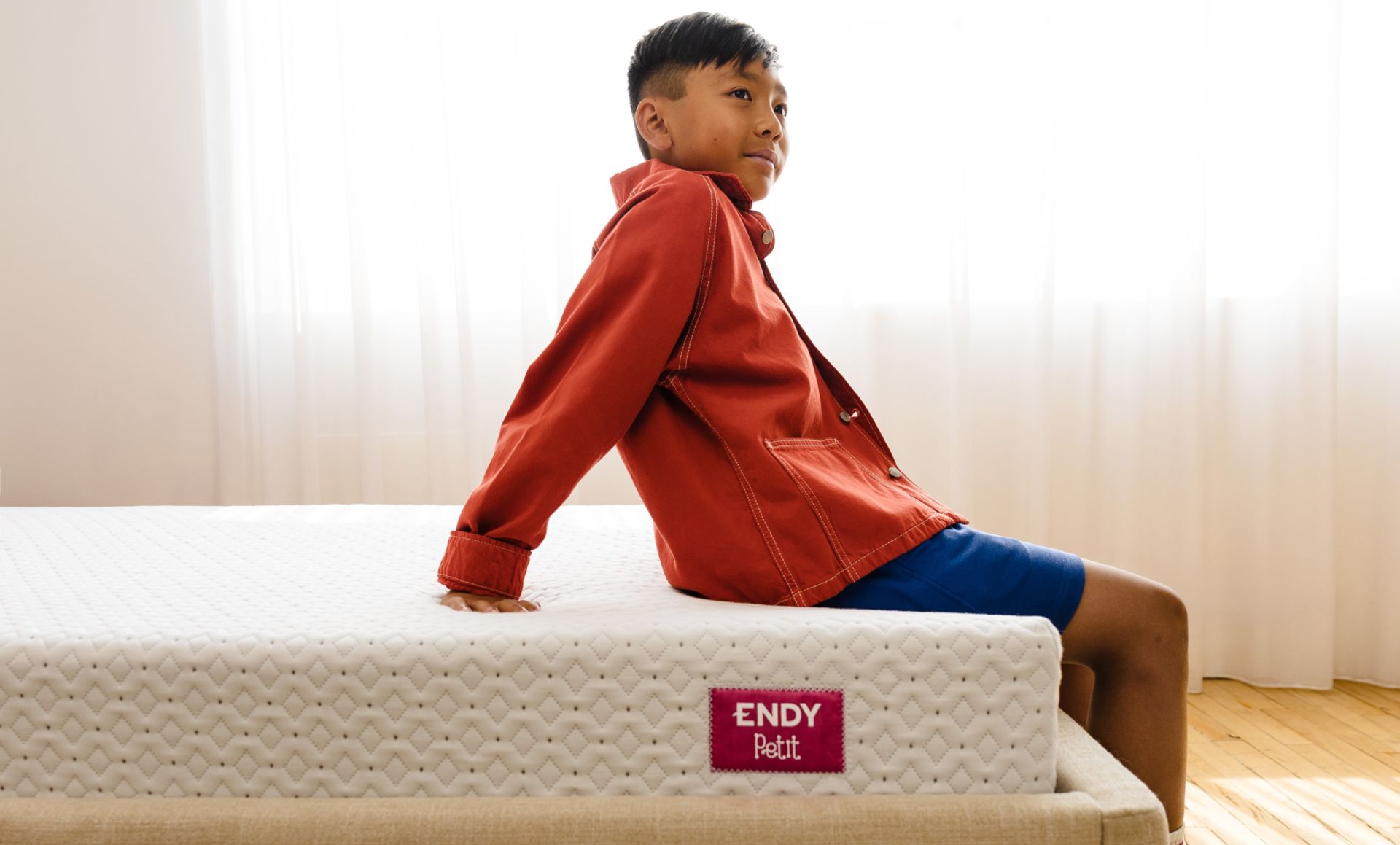 A child sitting on the Endy Petit Mattress.