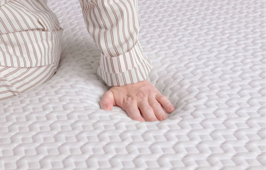 Close up of the surface of the mattress, a hand pushes on it