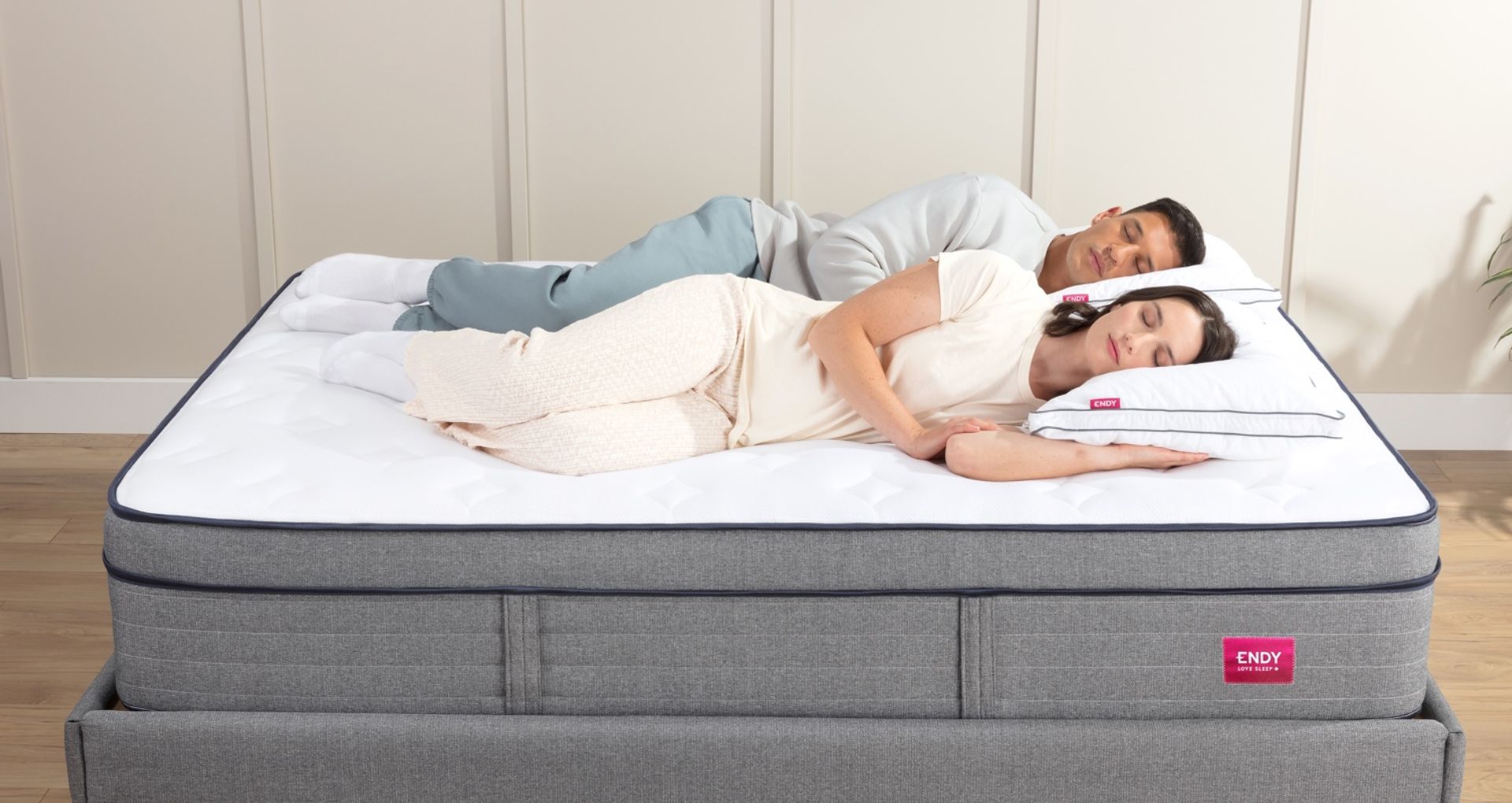 A man and woman lying side by side, on their sides, sleeping.