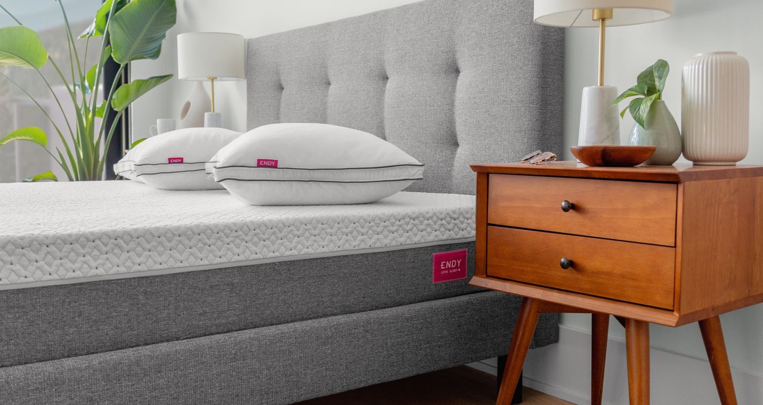 Two Endy Customizable Pillows sitting atop the Endy Mattress accompanied by the Endy Solid Wood Nightstand