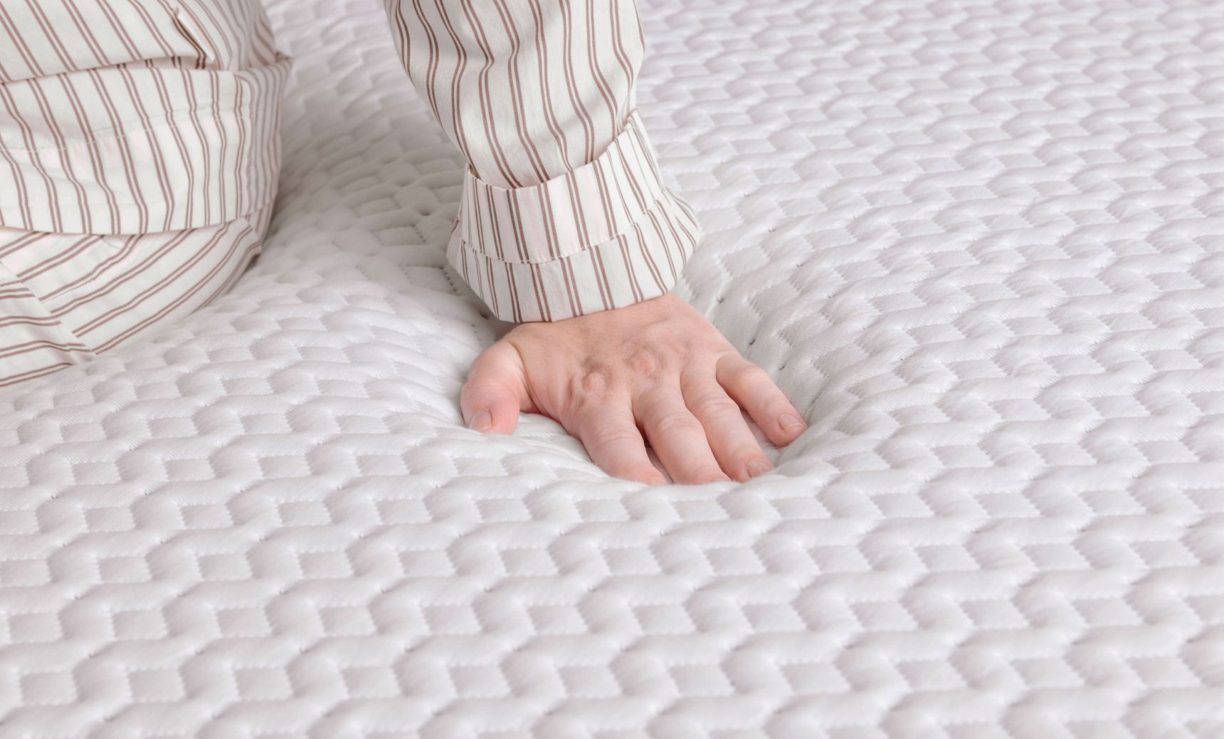 Close up of the surface of the Endy Mattress, a person in striped pajamas pushes down on it