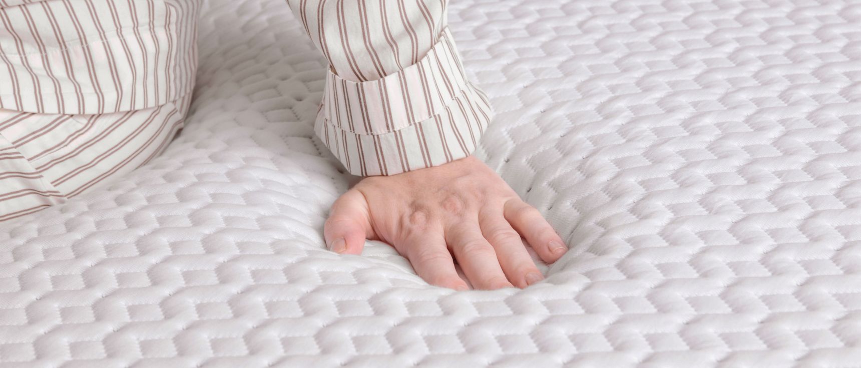 Close up of the surface of the Endy Mattress, a person in striped pajamas pushes down on it