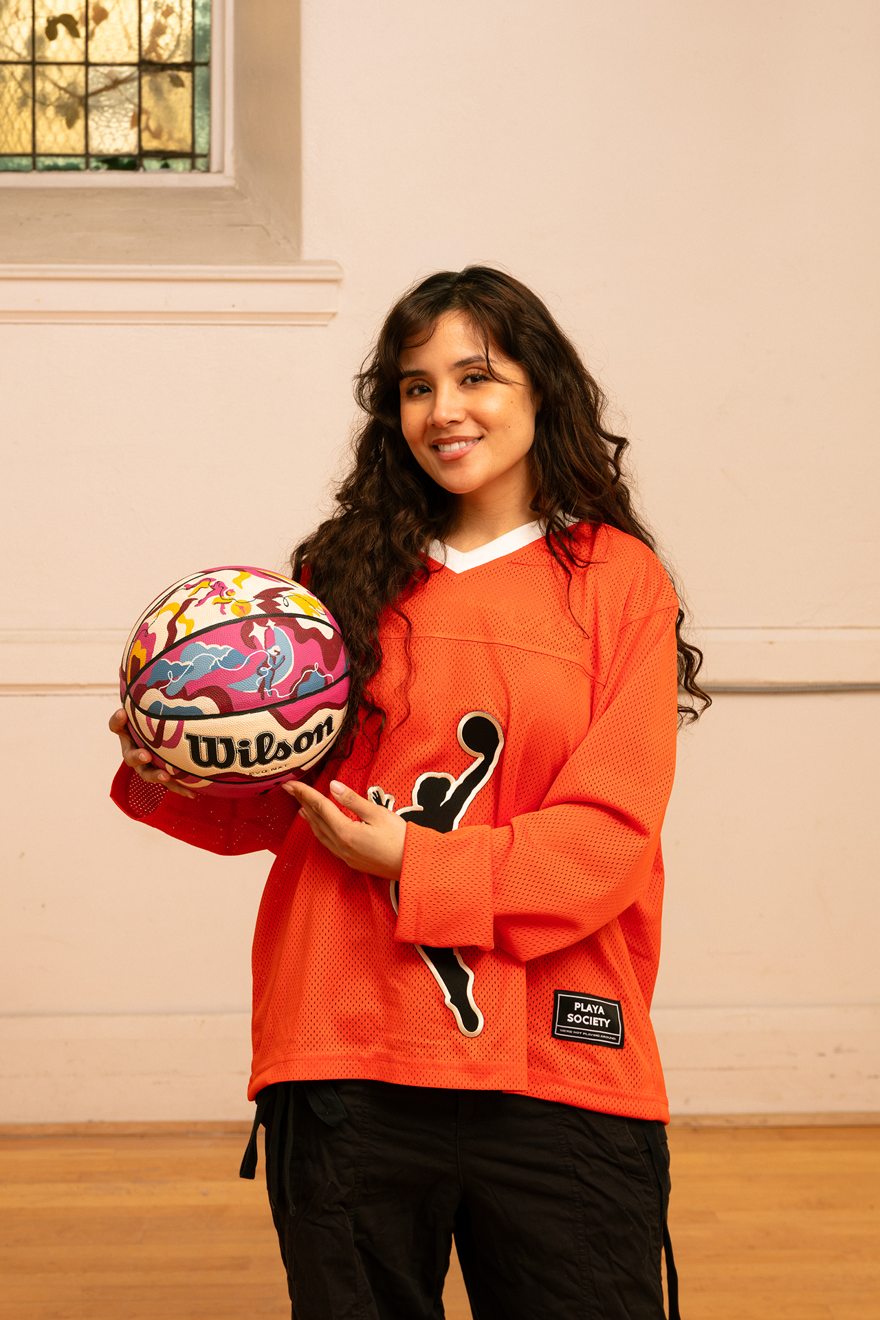 Artist Erika Flores holding the custom Endy x WNBA basketball she designed.