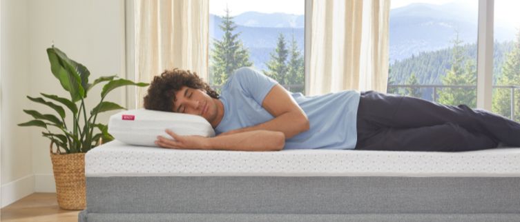 A person snoozing on an Endy Mattress and using an Endy Memory Foam Pillow.