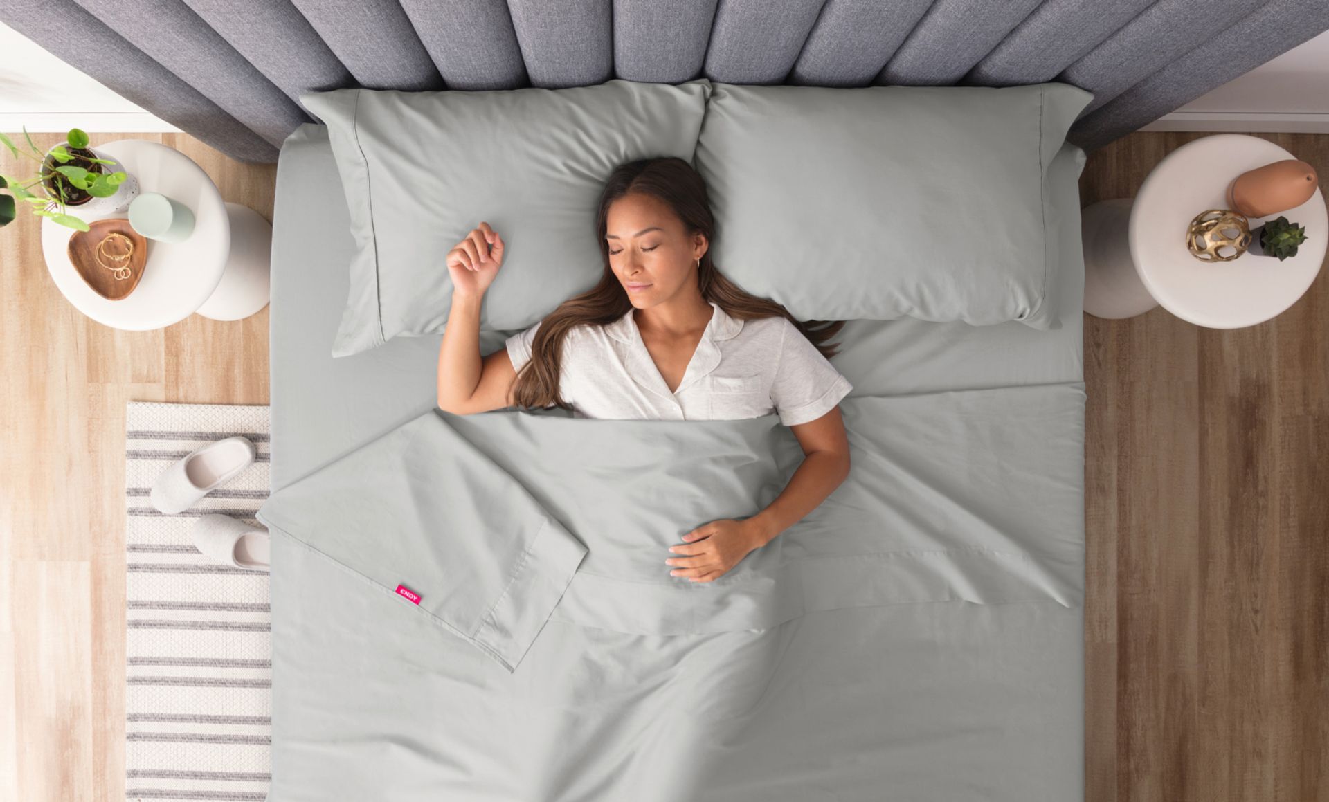 Woman sleeping under grey sheets in a Queen size bed