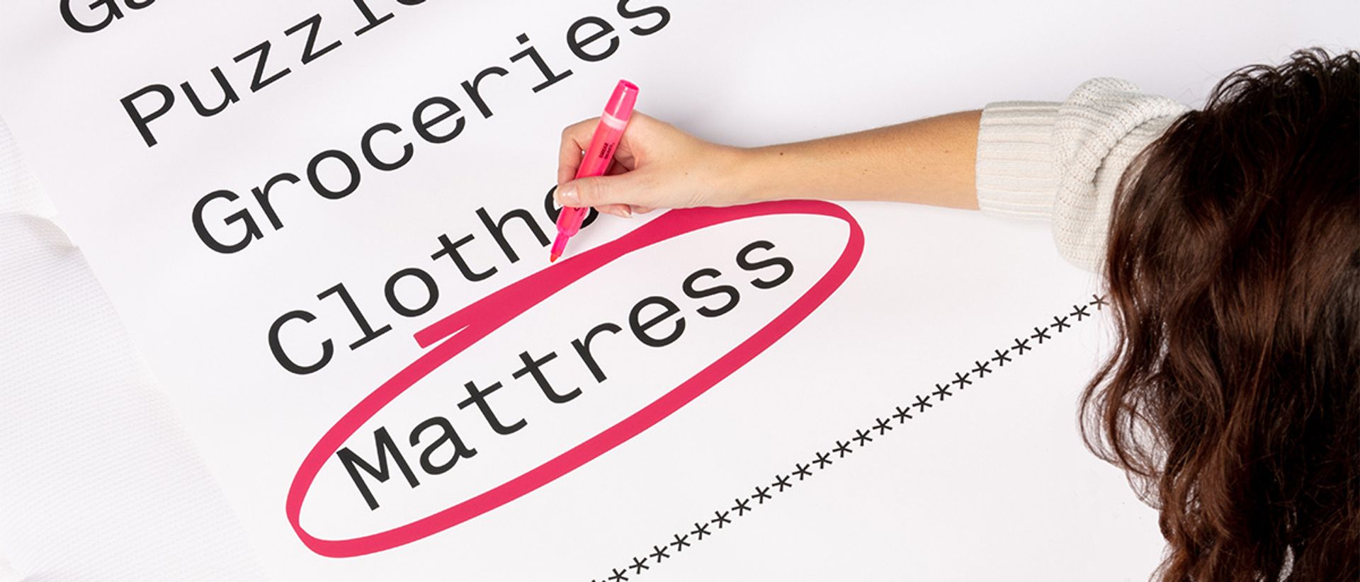 An oversized receipt with the word "mattress" being circled in pink marker by a woman.