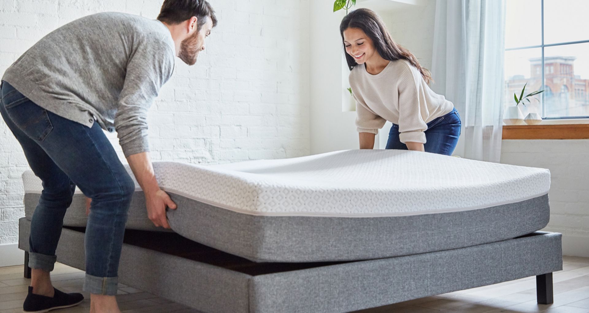 Two people placing an Endy Mattress on an Endy Platform Bed Frame.