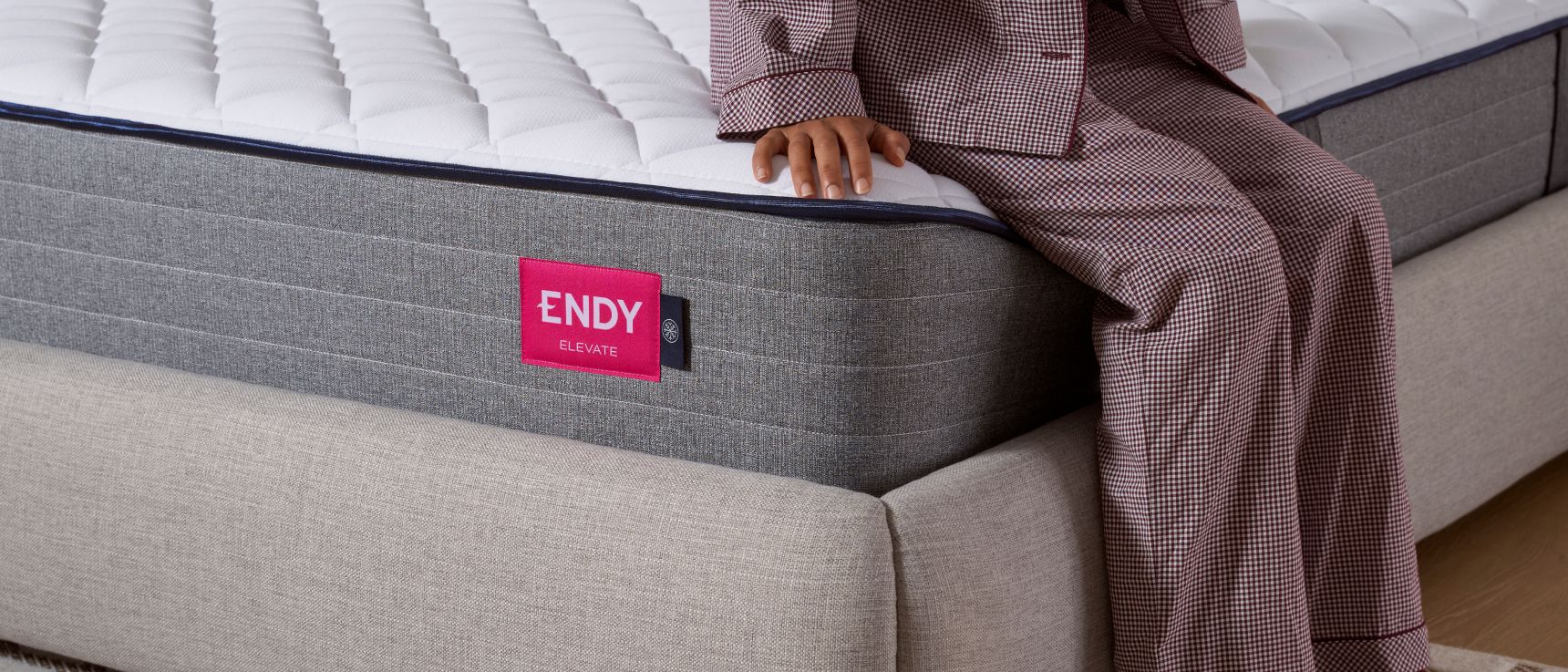 Close up of someone sitting on the corner of the Endy Elevate Hybrid in pajamas