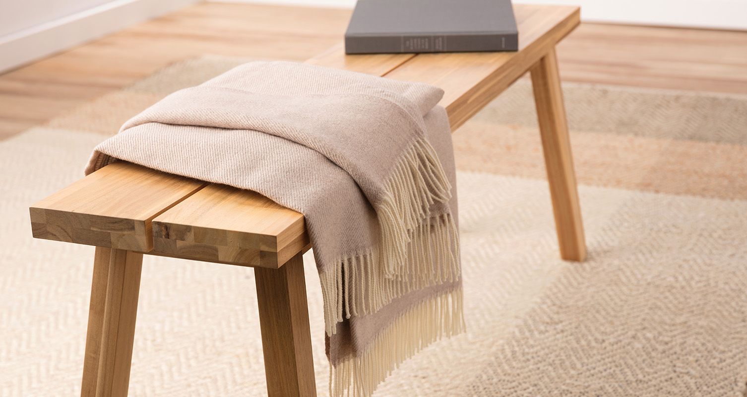 The Endy Merino Wool Throw Blanket laid out on a wooden bench
