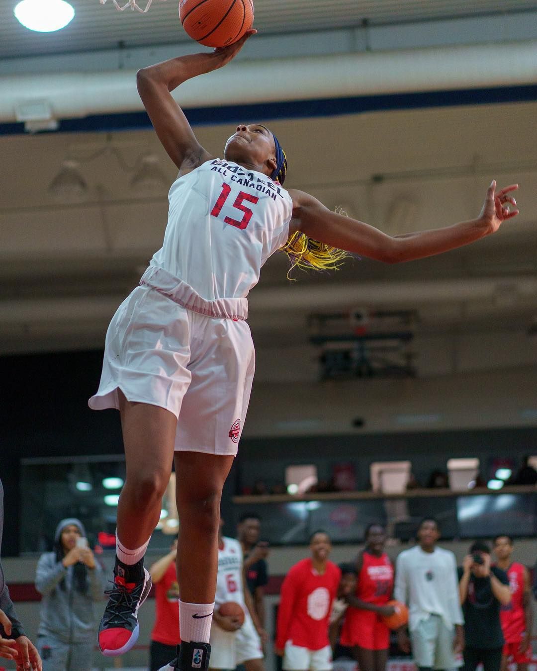 Aaliyah Edwards scores a basket in a white basketball uniform