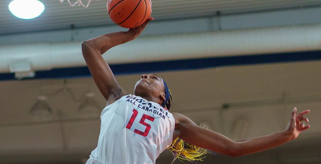 Aaliyah Edwards scores a basket in a white basketball uniform
