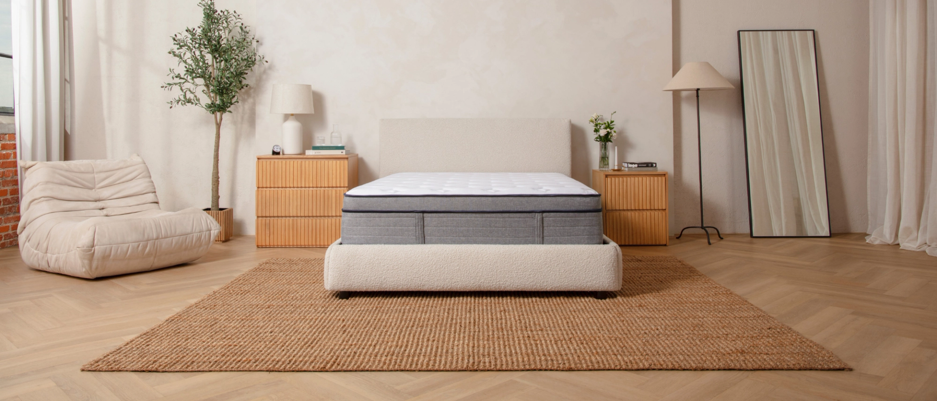 Bare Endy Hybrid mattress on a white upholstered bedframe in a beige bedroom