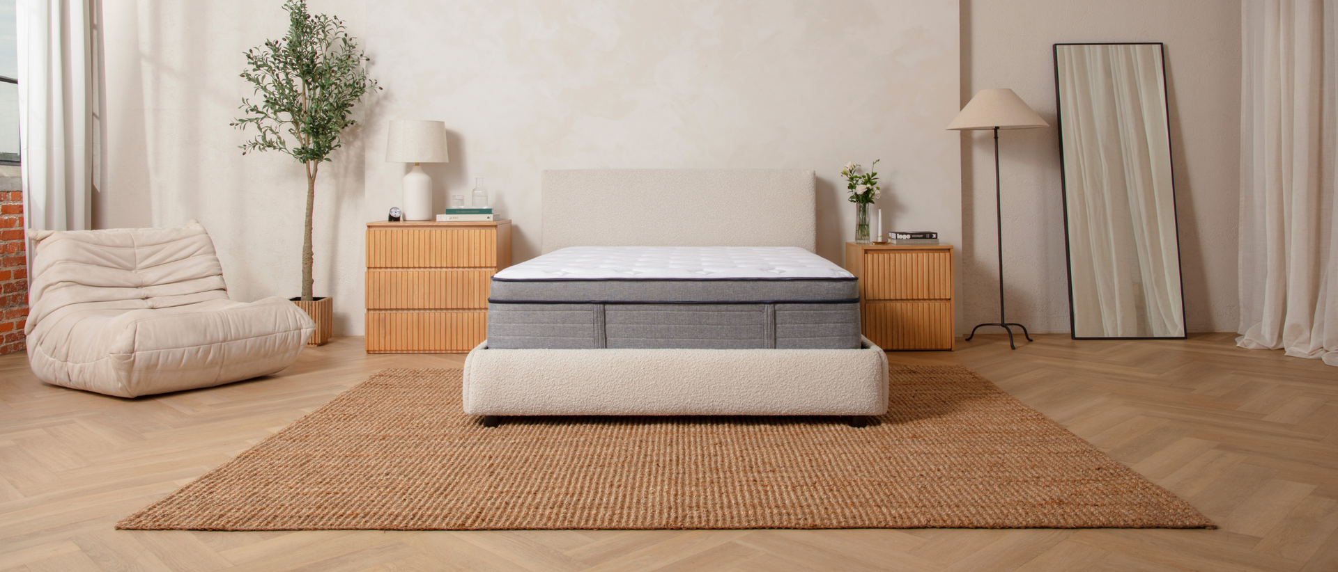Bare Endy Hybrid mattress on a white upholstered bedframe in a beige bedroom