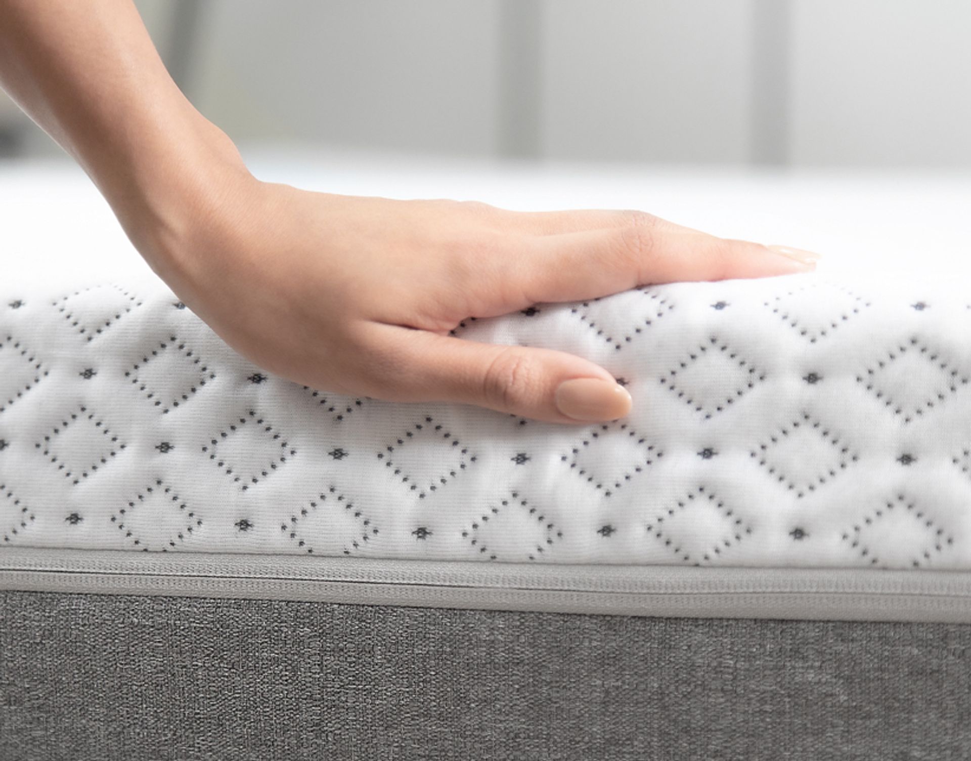 A person's hand on top of the Endy Mattress's quilted out layer surface.