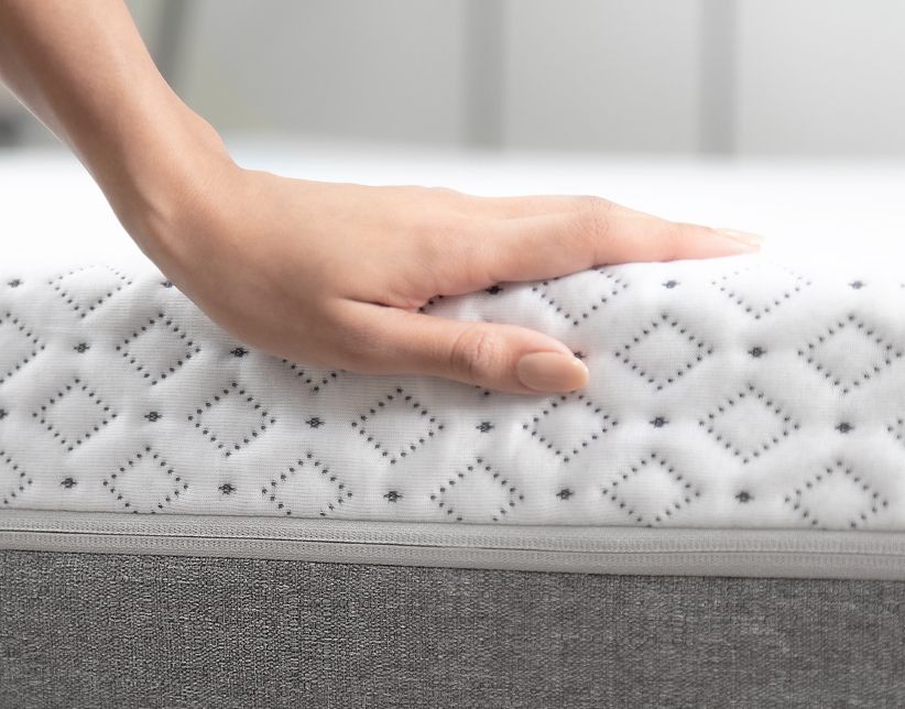 A person's hand on top of the Endy Mattress's quilted out layer surface.