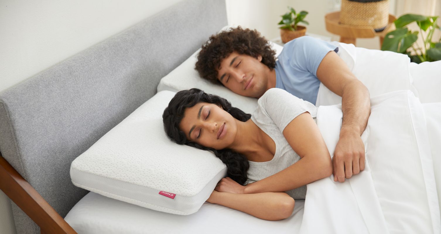 Two people snoozing in an Endy Solid Wood Bed with Endy Memory Foam Pillows.