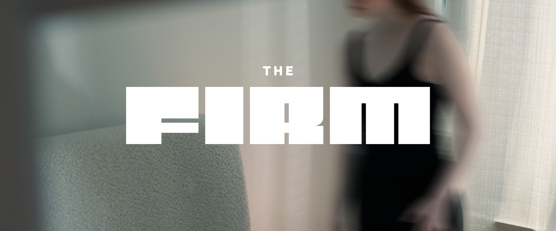"The Firm" written in bold copy on top of a blurry image of a woman standing in a bedroom